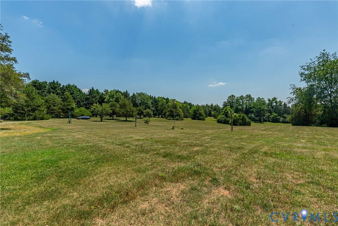 Expansive grassy terrain featuring scattered trees and a dense tree line bordering the property