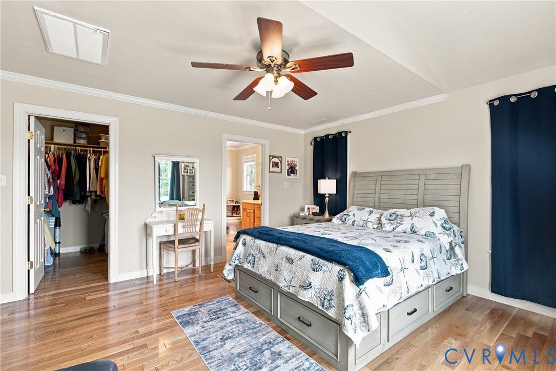 Vaulted ceiling with a ceiling fan, hardwood flooring, and a walk-in closet with double doors