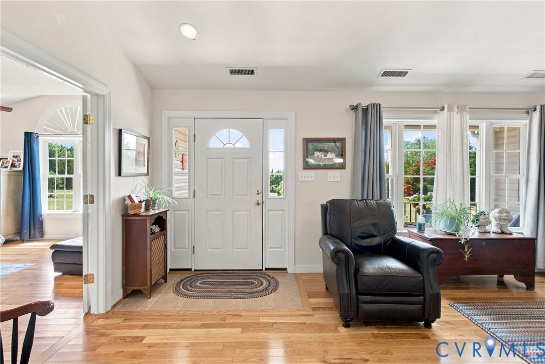 Entryway featuring hardwood flooring, a white paneled door with an arched transom, and sidelight windows