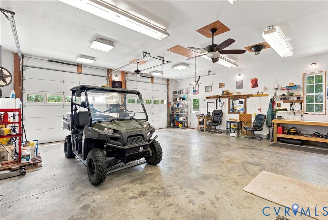 Spacious garage featuring a concrete floor, multiple ceiling fans, and overhead lighting