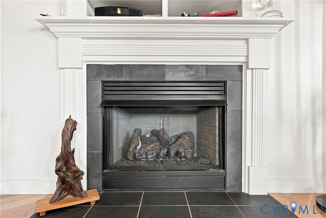Fireplace featuring a classic white mantel, black tile surround, and an integrated firebox with a screen