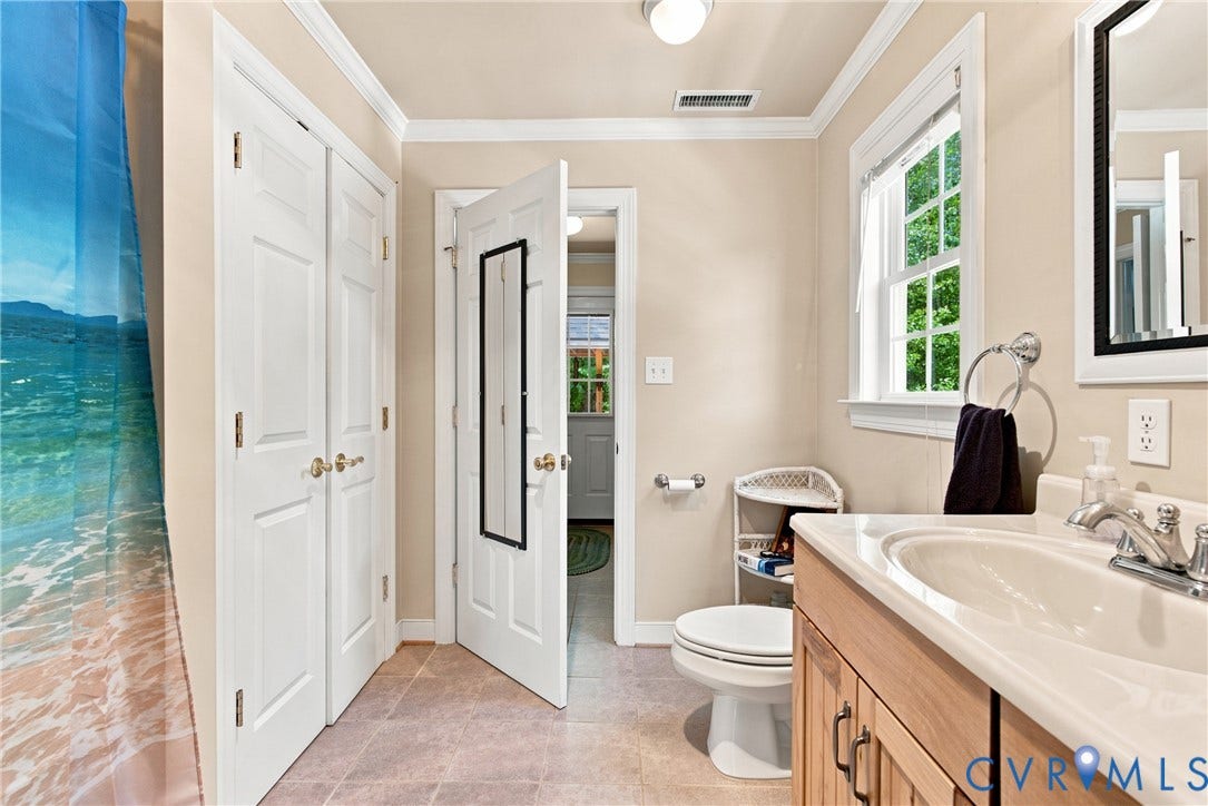 Bathroom featuring a light wood-finish vanity with an integrated sink, polished chrome faucet, and a wall-mounted mirror