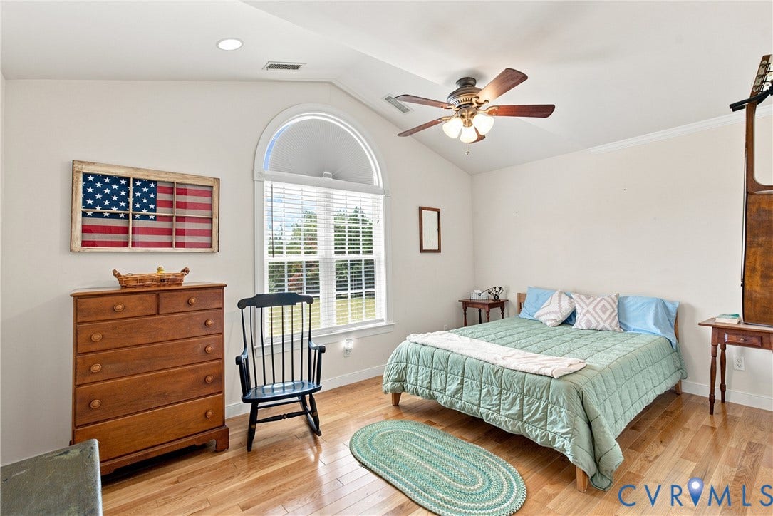 Vaulted ceiling bedroom with an arched window, wood-finish flooring, recessed lighting, and a ceiling fan