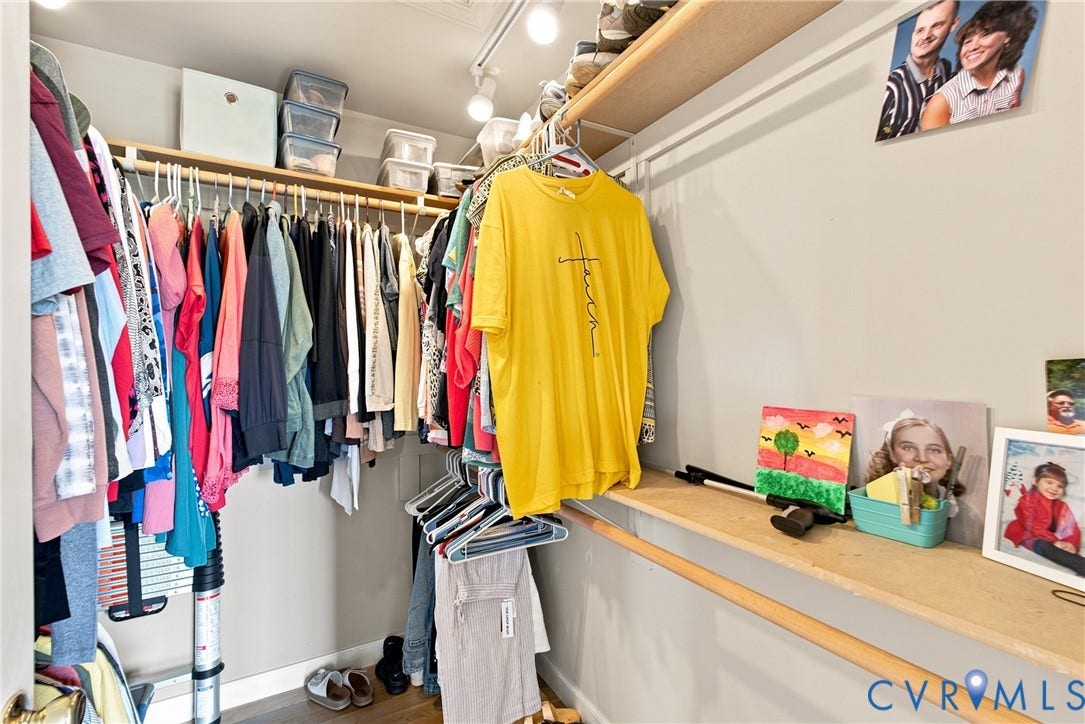Walk-in closet featuring track lighting, multiple hanging rods, and integrated shelving
