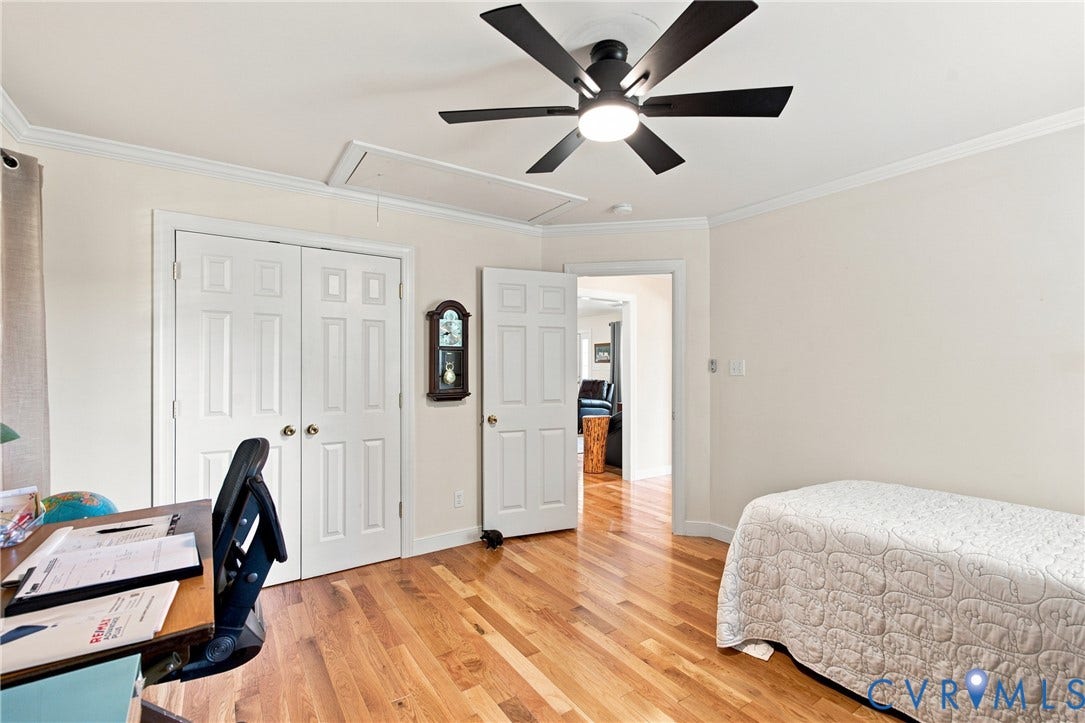 Room featuring wood-finish flooring, a contemporary ceiling fan with integrated lighting, crown molding, and two-panel interior doors