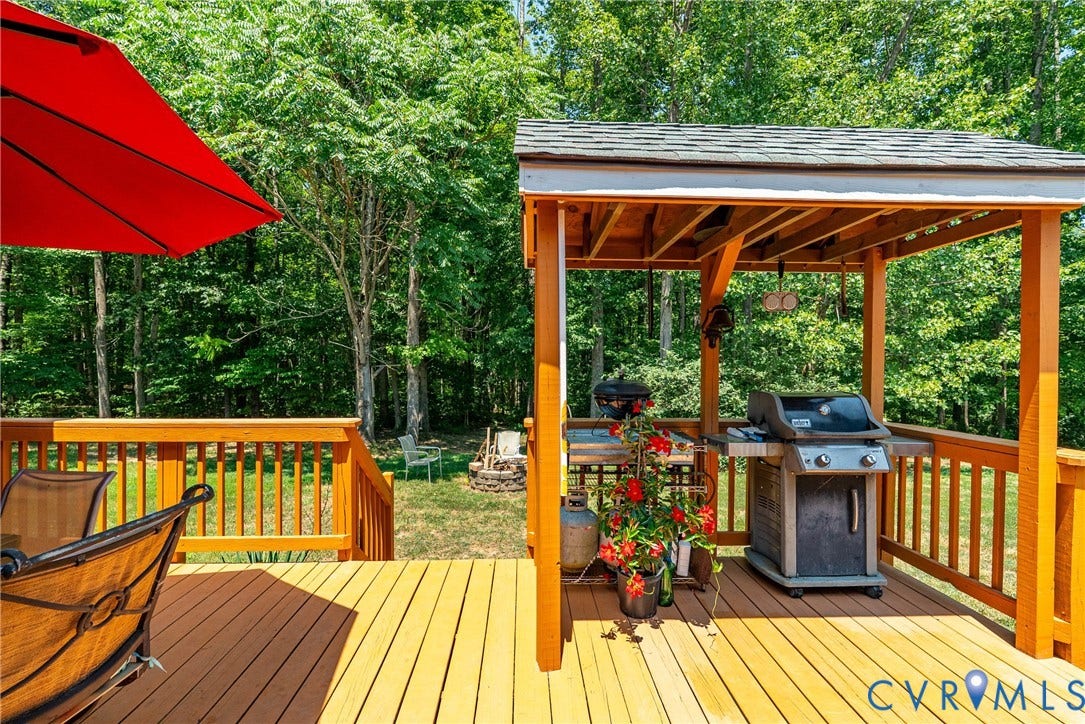 Spacious wood-finish deck with a built-in pergola, offering an outdoor grilling station