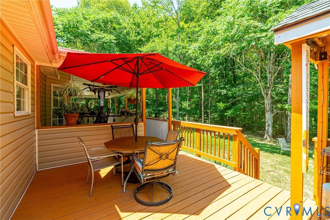 Multi-level exterior deck with a wood-finish surface, wood railings, and stairs leading to a grassy area
