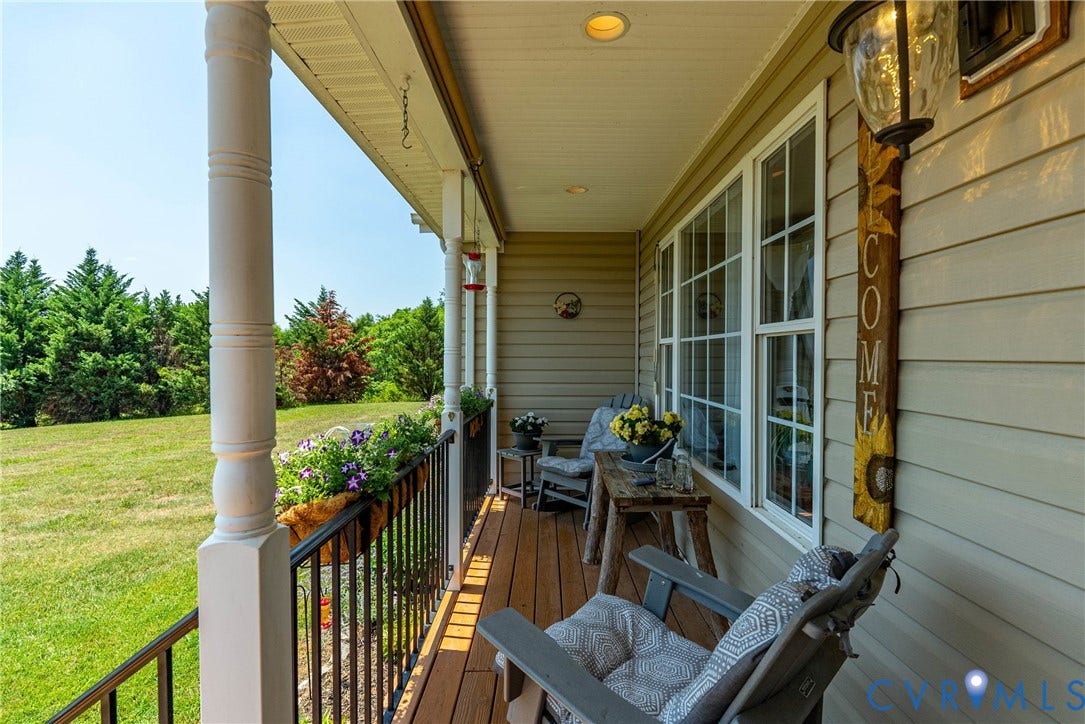 Covered front porch featuring wood-finish flooring, white architectural columns, black iron railings, and recessed lighting