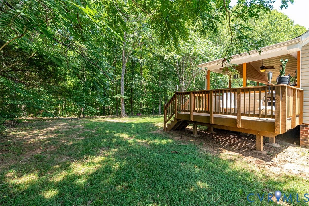Expansive wooden deck with a covered overhead structure, perimeter railing, and integrated stairs
