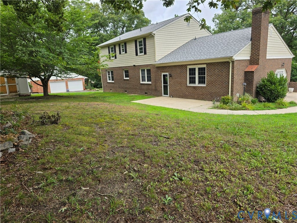 3901 Buckland Place, Chester, VA 23831 Brick and siding exterior featuring multiple windows with dark shutters, a prominent brick chimney, and a concrete patio
