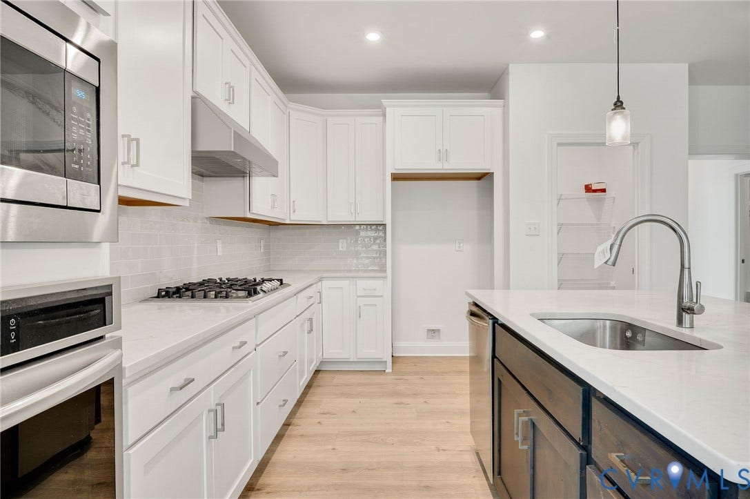 7130 Maple Summit Lane, Moseley, VA 23120 Contemporary kitchen featuring white shaker cabinetry, stainless steel appliances, a gas cooktop, light wood-finish flooring, and a kitchen island with an undermount sink