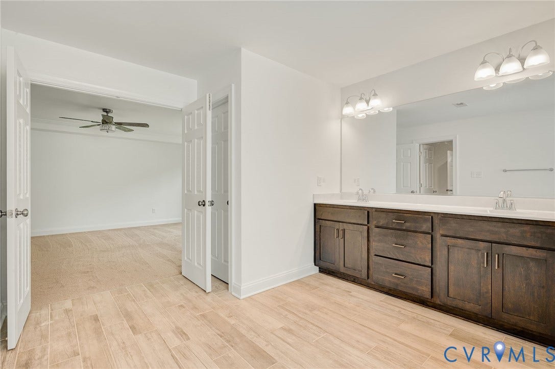 7130 Maple Summit Lane, Moseley, VA 23120 Double vanity with dual sinks and light-colored countertops, set against wood-finish flooring
