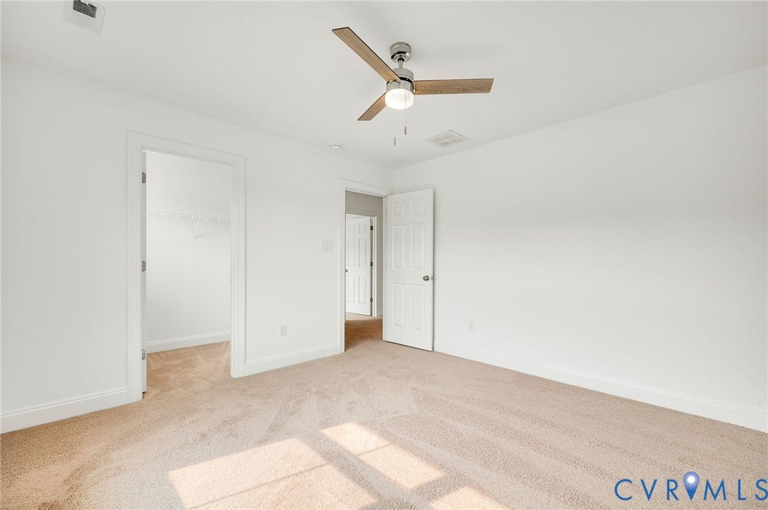 7130 Maple Summit Lane, Moseley, VA 23120 Carpeted room with white walls, featuring a ceiling fan with light, a walk-in closet with wire shelving, and a paneled interior door