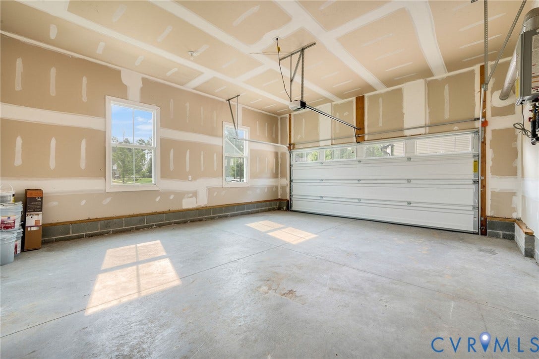 7130 Maple Summit Lane, Moseley, VA 23120 Spacious garage with unfinished walls, concrete flooring, two windows, and an overhead door with transom windows