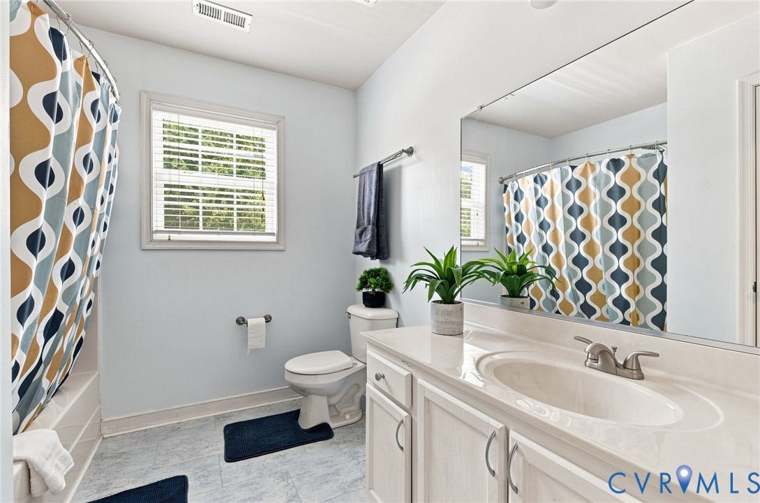 Bathroom featuring a white vanity with an integrated sink, brushed nickel faucet, a large mirror, and tiled flooring