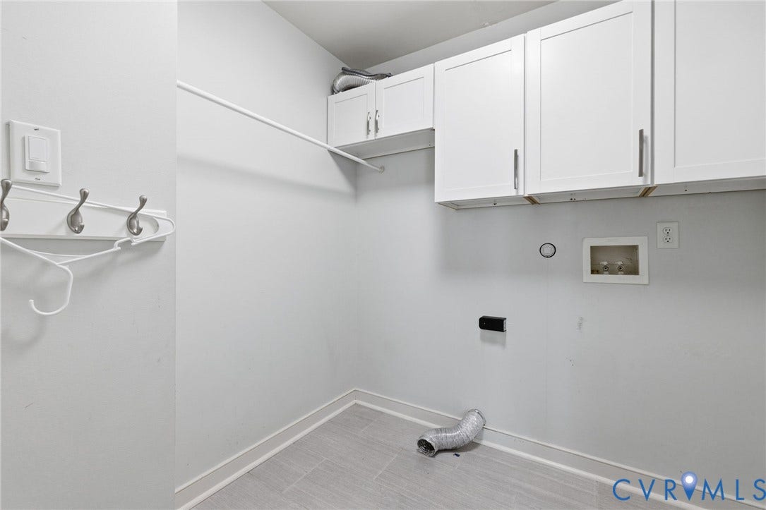 Dedicated laundry space featuring white shaker-style cabinetry, a hanging rod, and light gray tile flooring