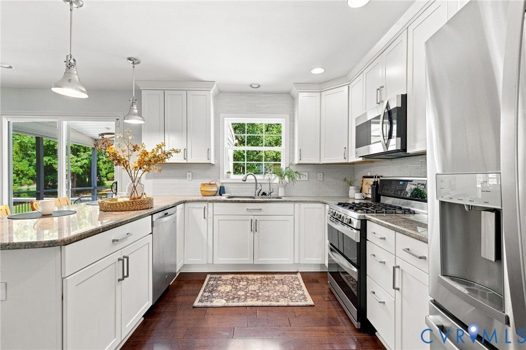 Kitchen featuring white shaker cabinetry, stainless steel appliances, wood-finish flooring, and a stone countertop peninsula with pendant lighting