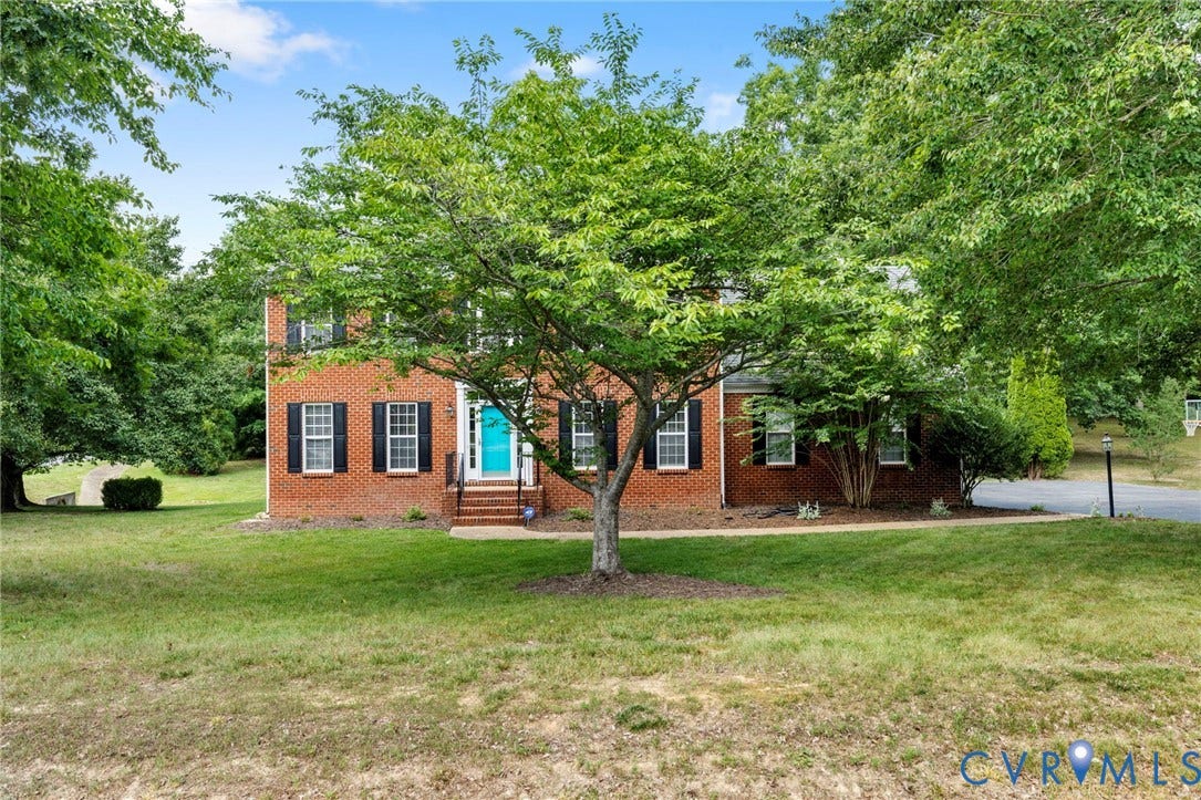 Brick-front residence featuring a turquoise entry door, white trim, and black shutters
