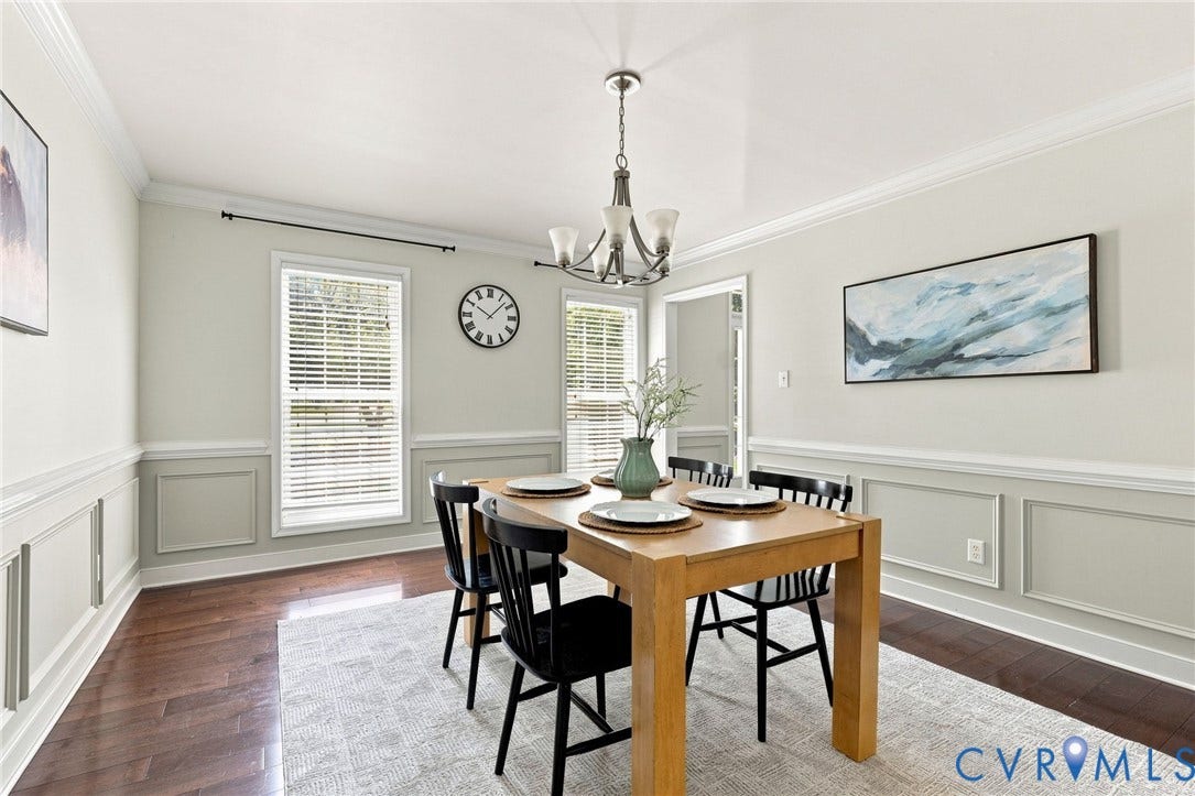Hardwood-finish flooring, crown molding, wainscoting, double windows with blinds, and a chandelier