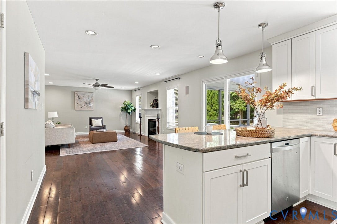 Hardwood-style flooring throughout, recessed lighting, white kitchen cabinetry, stainless steel dishwasher, and a built-in fireplace