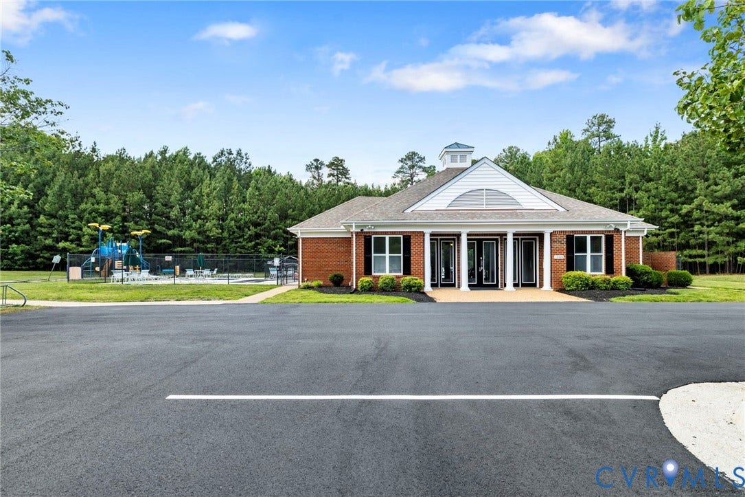 Community clubhouse featuring a brick exterior, white siding, a cupola, and a covered portico entrance with white columns
