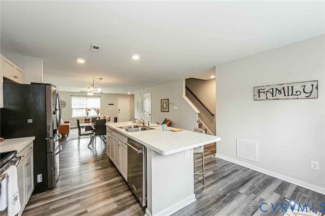 1324 Stone Ridge Park Loop, Henrico, VA 23228 Kitchen featuring an expansive island with a stainless steel double sink and dishwasher, white cabinetry, and a light-toned countertop