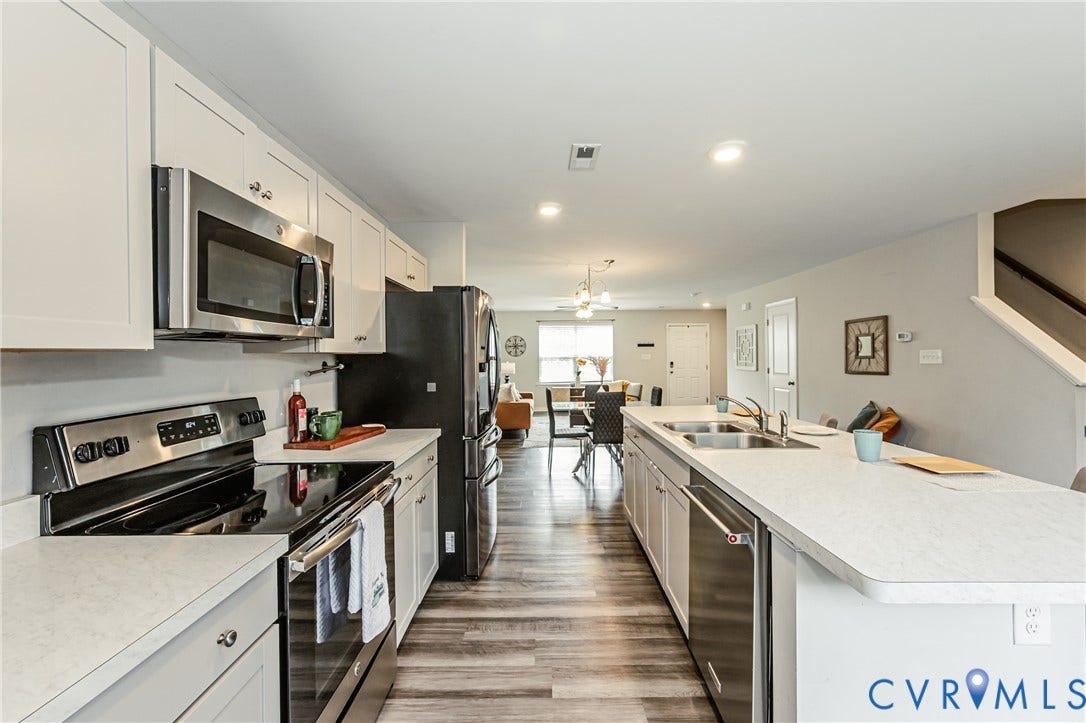 1324 Stone Ridge Park Loop, Henrico, VA 23228 Open-concept kitchen featuring an island with dual sinks, stainless steel appliances, white cabinetry, wood-finish flooring, and recessed lighting