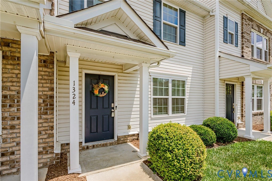 1324 Stone Ridge Park Loop, Henrico, VA 23228 Inviting front entrance featuring a dark paneled door, white columns, brick facade accents, and horizontal siding