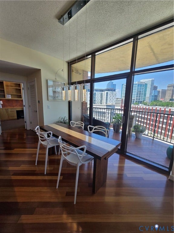 1101 Haxall Point, #815, Richmond, VA 23219 Spacious dining area featuring multi-tone wood-finish flooring, a contemporary linear pendant light fixture, and a full-height window wall with balcony access