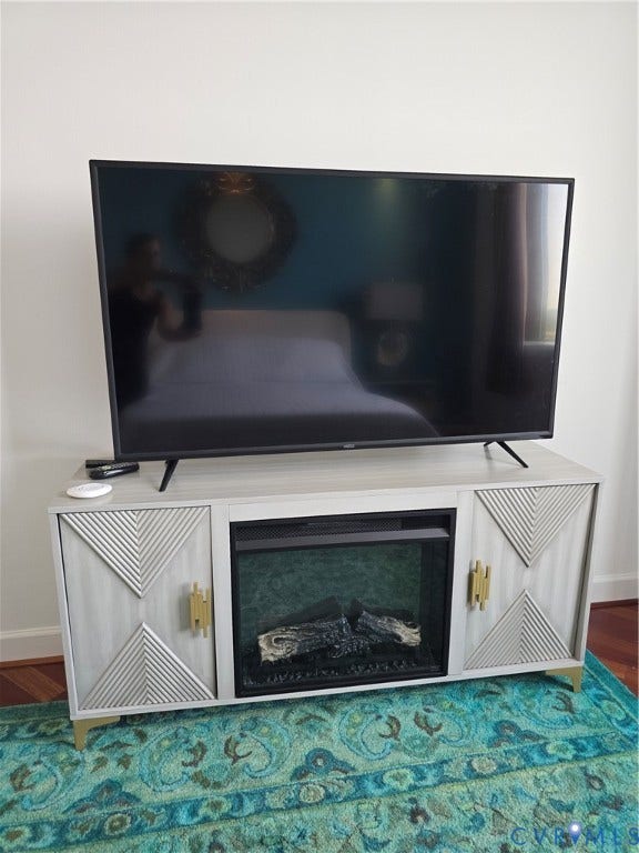 1101 Haxall Point, #815, Richmond, VA 23219 Modern entertainment console featuring a built-in electric fireplace, light wood-finish cabinetry, patterned door fronts, and gold-tone hardware