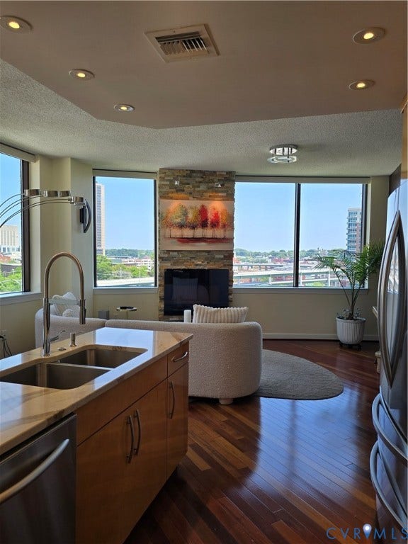1101 Haxall Point, #815, Richmond, VA 23219 Open-concept living area featuring rich wood-finish flooring, a kitchen island with an undermount dual-basin sink, and a stone-clad fireplace