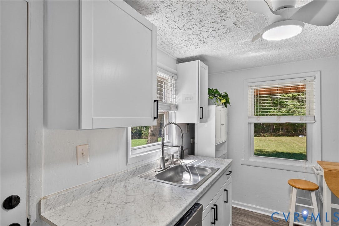 13070 Auburn Mill Road, Glen Allen, VA 23059 Kitchen sink area featuring light-toned countertops, white cabinetry with black hardware, and an undermount double-basin sink with a gooseneck faucet