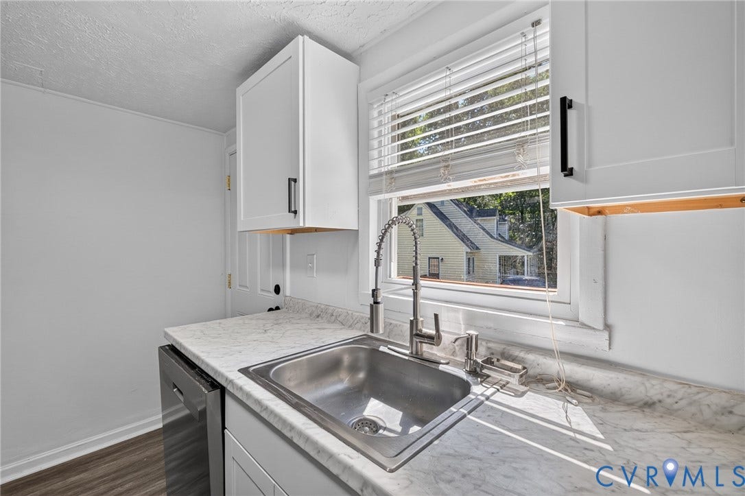 13070 Auburn Mill Road, Glen Allen, VA 23059 Kitchen area featuring white shaker-style cabinetry with matte black hardware, a stainless steel sink with a gooseneck faucet, light-toned countertops, a built-in dishwasher, and wood-finish flooring
