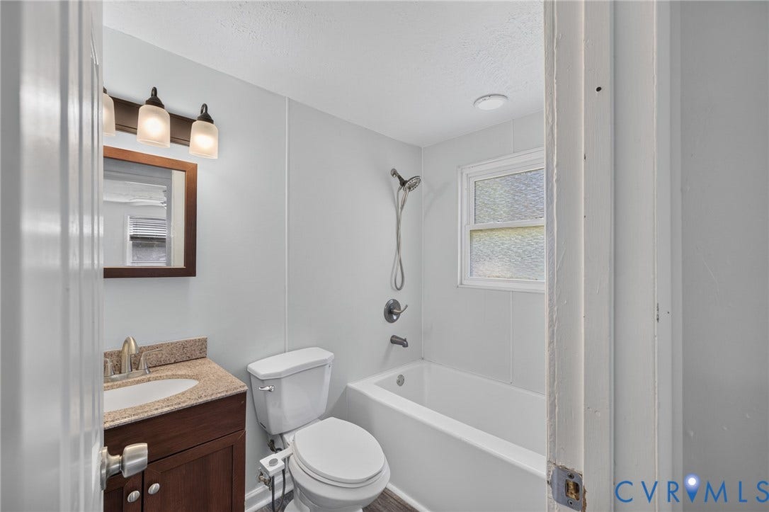 13070 Auburn Mill Road, Glen Allen, VA 23059 Bathroom featuring a wood-finish vanity with a speckled countertop and undermount sink, a three-light fixture, a toilet, and a bathtub with showerhead