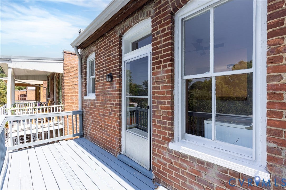 3135 Floyd Avenue, Museum District, Richmond, VA 23221 Exterior brick wall featuring a painted wood deck with white railings, a white-framed window, and a white screen door