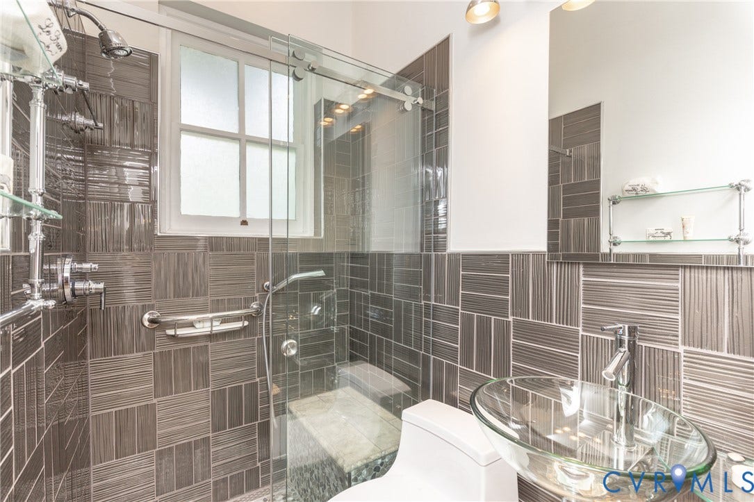 3135 Floyd Avenue, Museum District, Richmond, VA 23221 Glass-enclosed shower with a built-in bench, full-height tile, and chrome fixtures