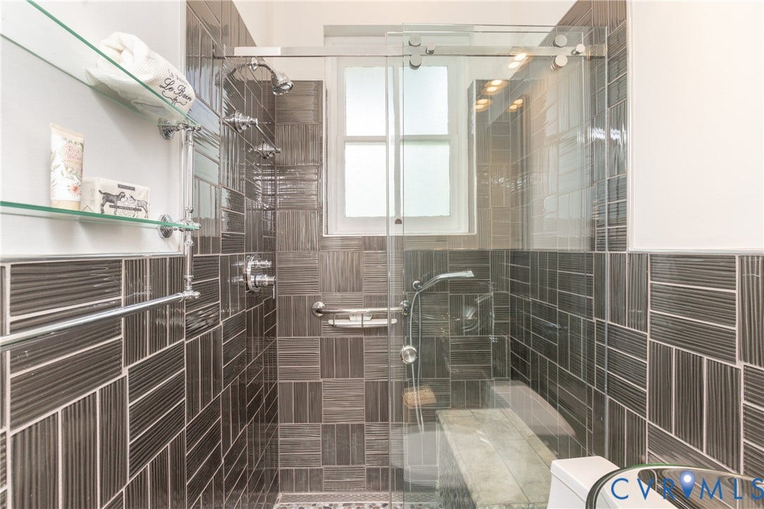 3135 Floyd Avenue, Museum District, Richmond, VA 23221 Glass-enclosed shower with dark rectangular tile walls, a built-in bench, and multiple shower fixtures