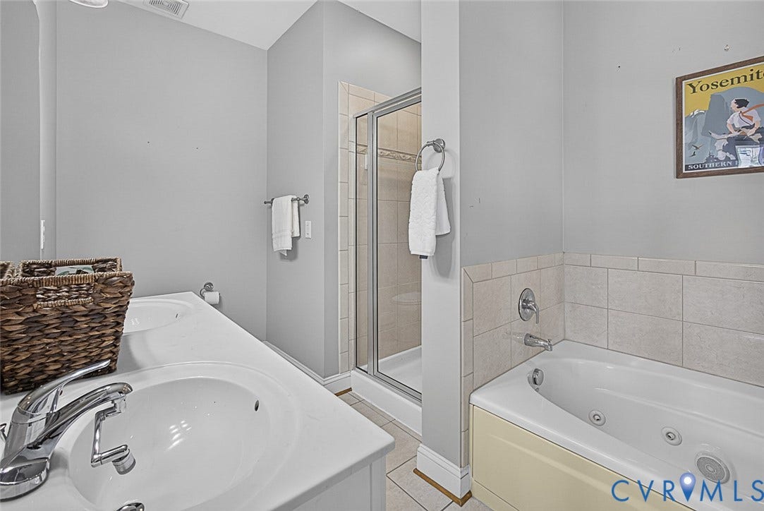 710 S Laurel Street, Oregon Hill, Richmond, VA 23220 Bathroom featuring a dual vanity, a glass-enclosed shower, a jetted soaking tub with tiled surround, and chrome fixtures