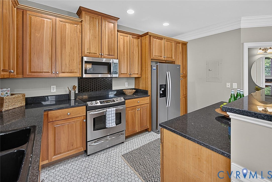 710 S Laurel Street, Oregon Hill, Richmond, VA 23220 Kitchen featuring wood cabinetry, stainless steel appliances, dark countertops, and a black hexagonal tile backsplash