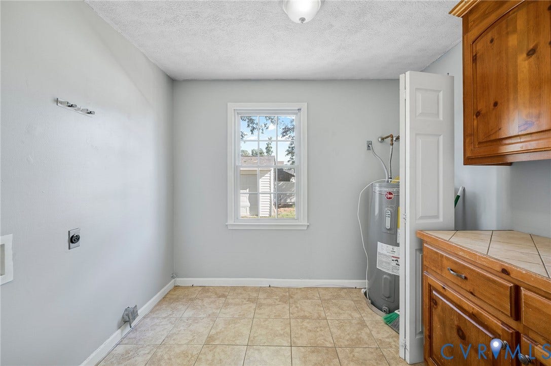 912 Williamsburg Road, Colonial Manor, Colonial Heights, VA 23834 Room featuring neutral wall tones, tile flooring, window with white trim, wood-finish cabinetry, and a tile countertop