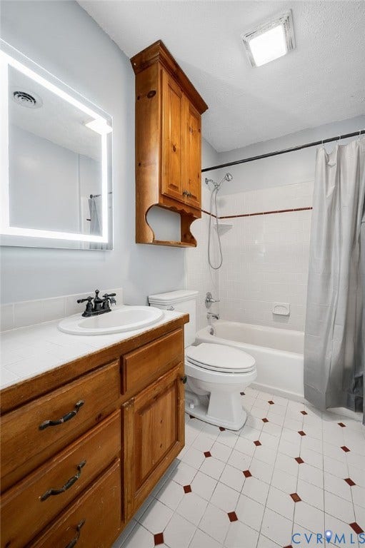912 Williamsburg Road, Colonial Manor, Colonial Heights, VA 23834 Vanity with wood-finish cabinetry, countertop with integrated sink, rectangular illuminated mirror, white tile flooring with accent squares, and a built-in bathtub with shower
