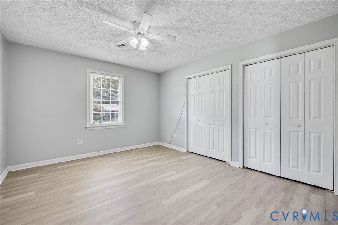 912 Williamsburg Road, Colonial Manor, Colonial Heights, VA 23834 Wood-finish flooring, two sets of bi-fold closet doors, a single window, and a ceiling fan with light fixture