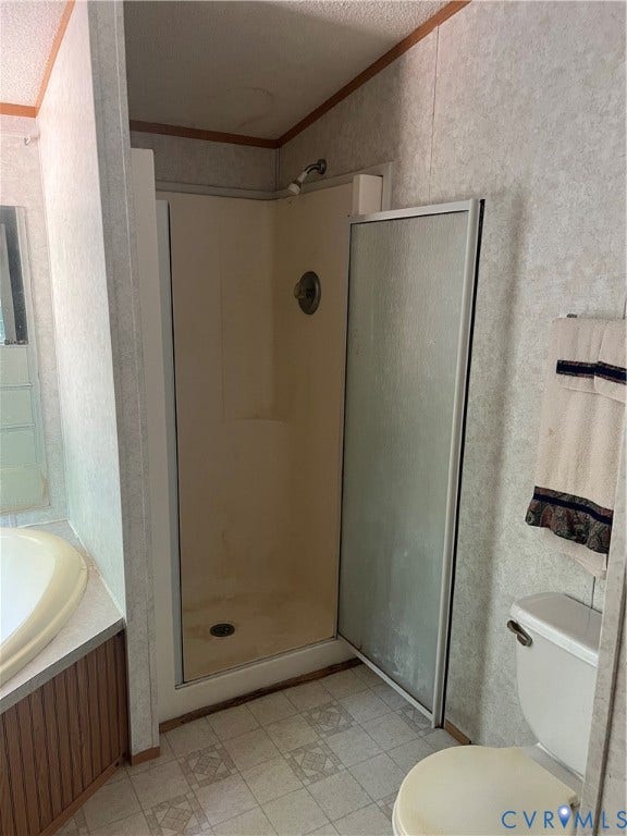 Shower stall with opaque glass door and chrome fixtures, geometric pattern vinyl flooring, and a portion of a built-in tub with wood-finish paneling