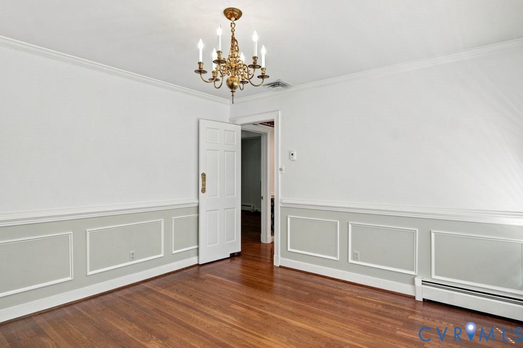 2425 Chancellor Road, North Chesterfield, VA 23235 Hardwood flooring, decorative wall paneling, crown molding, six-panel door, and a brass chandelier