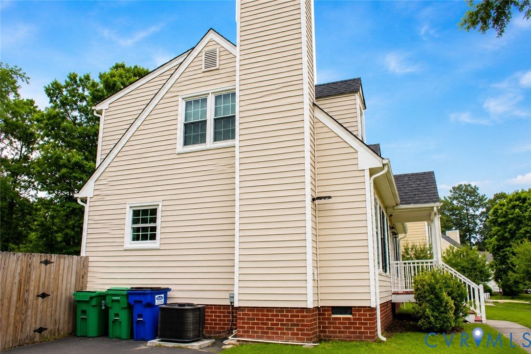 2120 Oakhampton Place, Henrico, VA 23233 Light-colored siding exterior featuring a prominent chimney, multiple windows, and a partial brick foundation