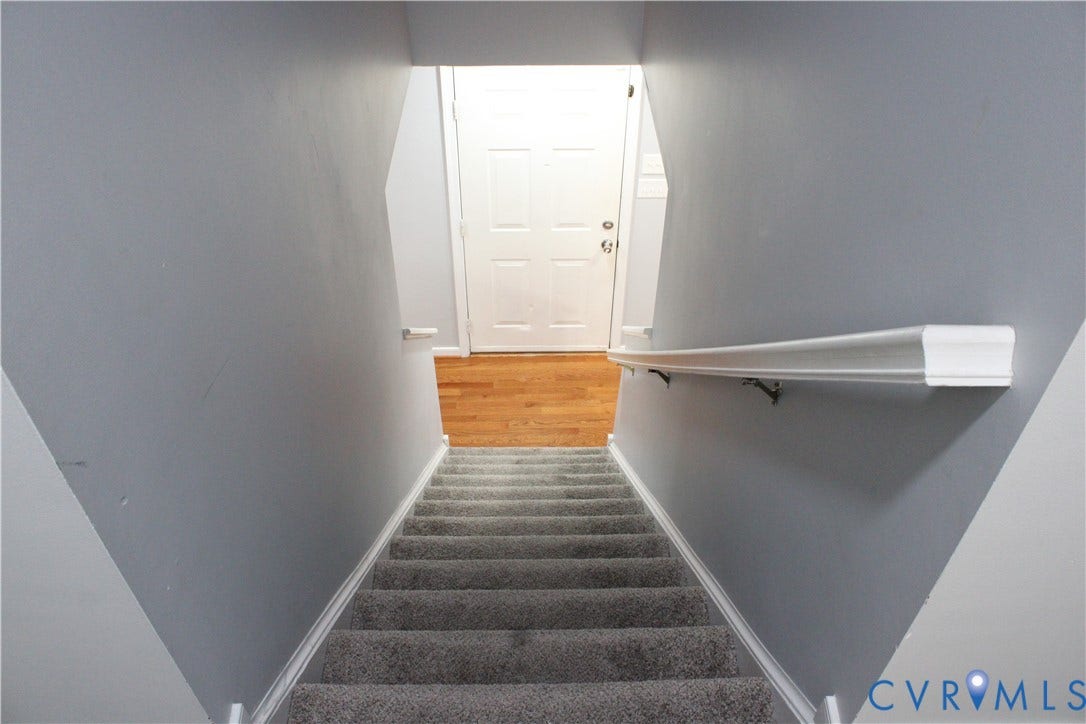 2120 Oakhampton Place, Henrico, VA 23233 Carpeted staircase with white handrail and baseboards, leading to a landing with wood-finish flooring and a white paneled door