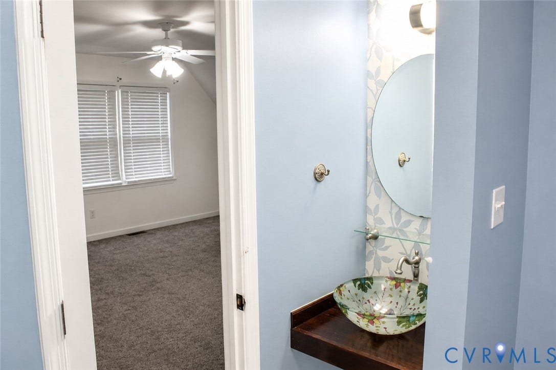 2120 Oakhampton Place, Henrico, VA 23233 Powder room featuring a decorative vessel sink, a floating wood-finish vanity, and a round mirror with overhead lighting
