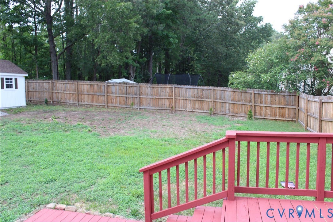 2120 Oakhampton Place, Henrico, VA 23233 Expansive backyard featuring a stained wood deck, a perimeter wood fence, and a white storage shed