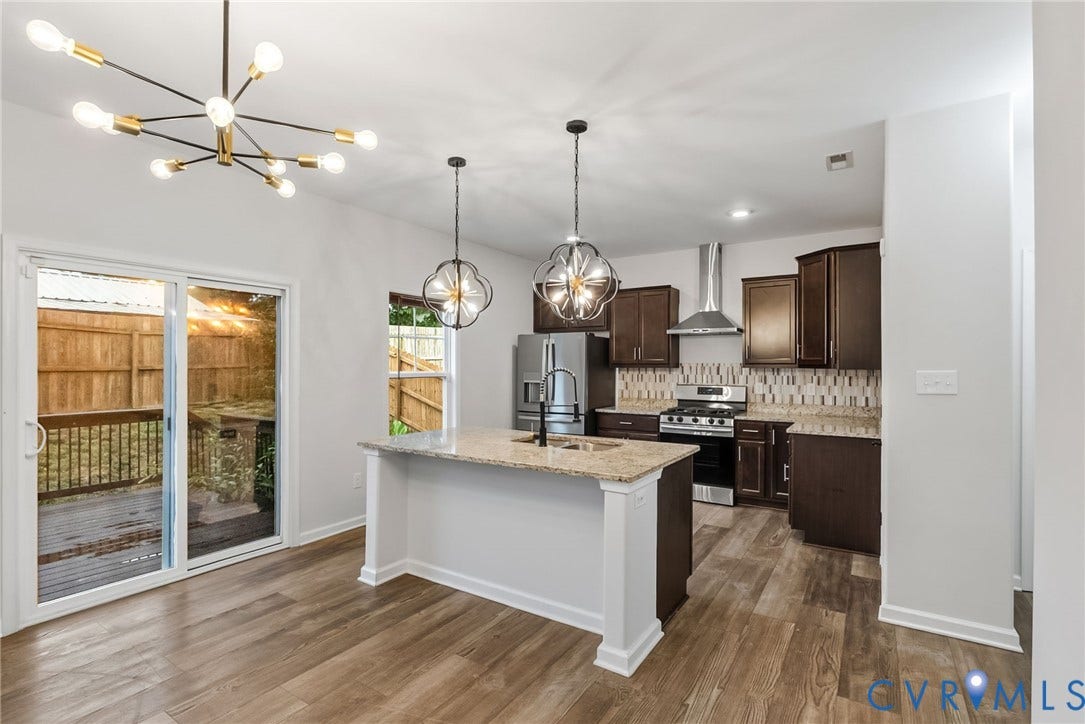 2007 Arcadia Avenue, Chester, VA 23831 Open-concept kitchen featuring an island with granite countertops, stainless steel appliances, wood-finish flooring, and direct access to an outdoor deck through sliding glass doors