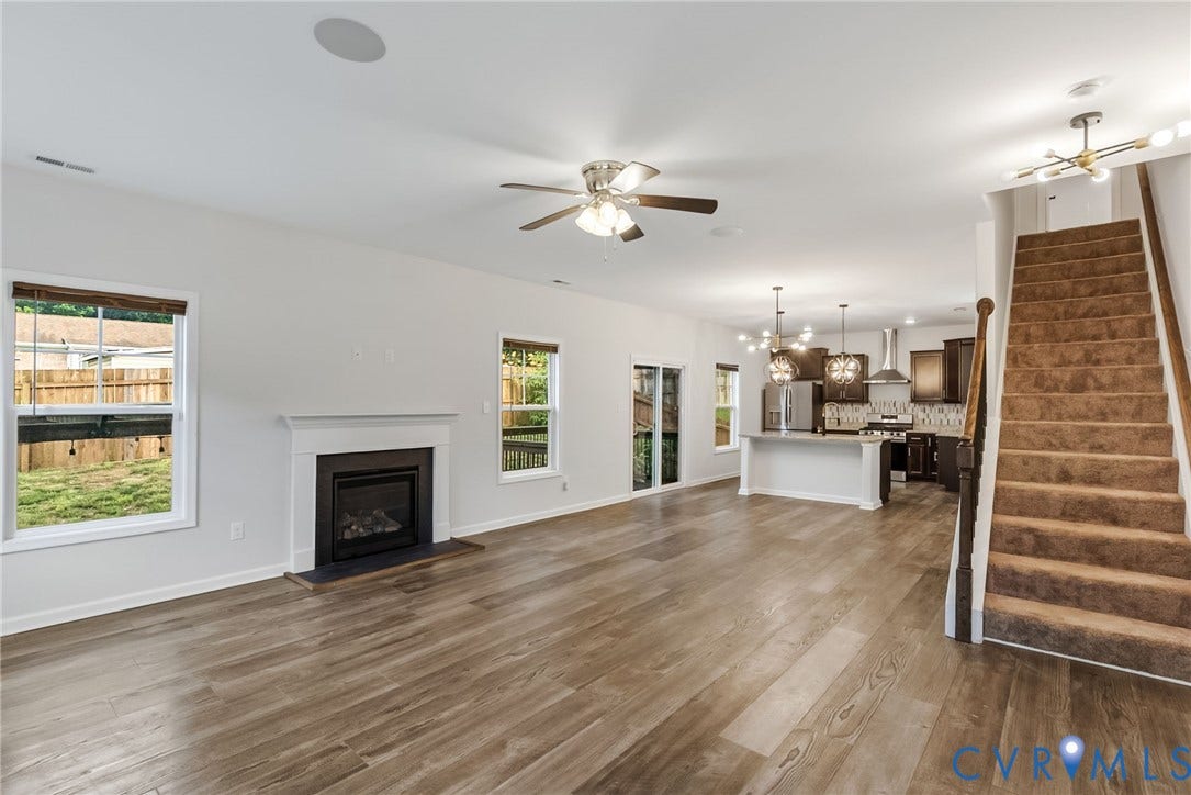 2007 Arcadia Avenue, Chester, VA 23831 Open-concept living area featuring wood-finish flooring, a fireplace with a white mantel, and a kitchen with an island